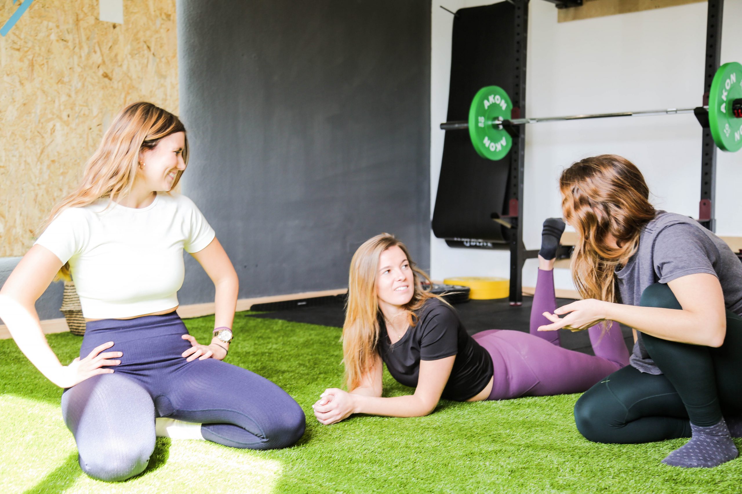 tres chicas contentas tras realizar ejercicio, hablando en el suelo